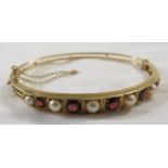 9 carat gold bangle set with six pearls and five graduated garnets, stamped 9 .375, safety chain,