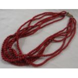 Triple-strand necklace of red coral beads, length about 44cm, with a clasp stamped 9CT