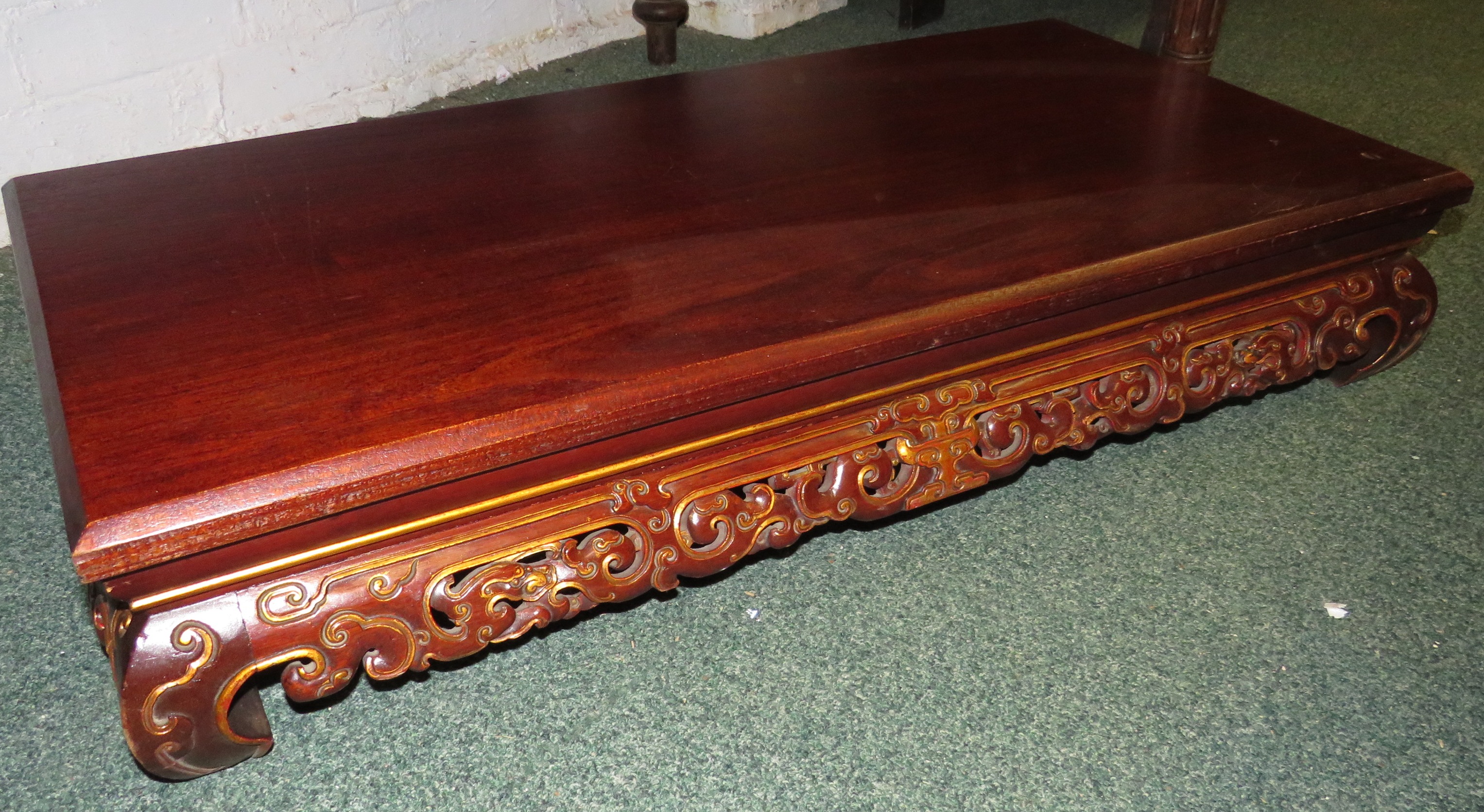 A 20th century oriental vase stand on scrolled feet, typically pierced frieze with red staining