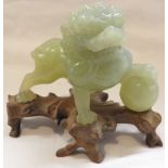 Chinese jade colour carved stone figure of Fo Dog (part tail missing), height including wooden stand