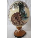 Hand painted and signed ostrich egg depicting African animals, on wooden stand, height 21cm