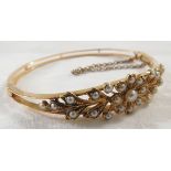 Yellow metal bangle with a foliate setting of twenty-four pearls (one absent), safety chain, no