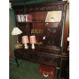 DARK OAK HEAVILY CARVED DRESSER WITH TWO DOORS TO TOP, RECESSES AND TWO DRAWERS TO BASE, STANDING ON