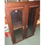 A dark mahogany bookcase with two glazed doors enclosing two columns fitted for adjustable