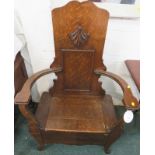 An oak monk's chair or hall seat, the backrest with rectangular moulding and a carved leaf, hinged