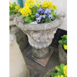 VERY LARGE URN WITH ROSE DECORATION STANDING ON SQUARE FLAT PLINTH WITH CONTENTS OF PANSIES AND