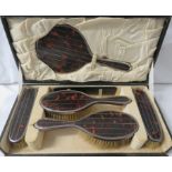 A cased five piece silver and tortoiseshell dressing table set comprising hand mirror and four