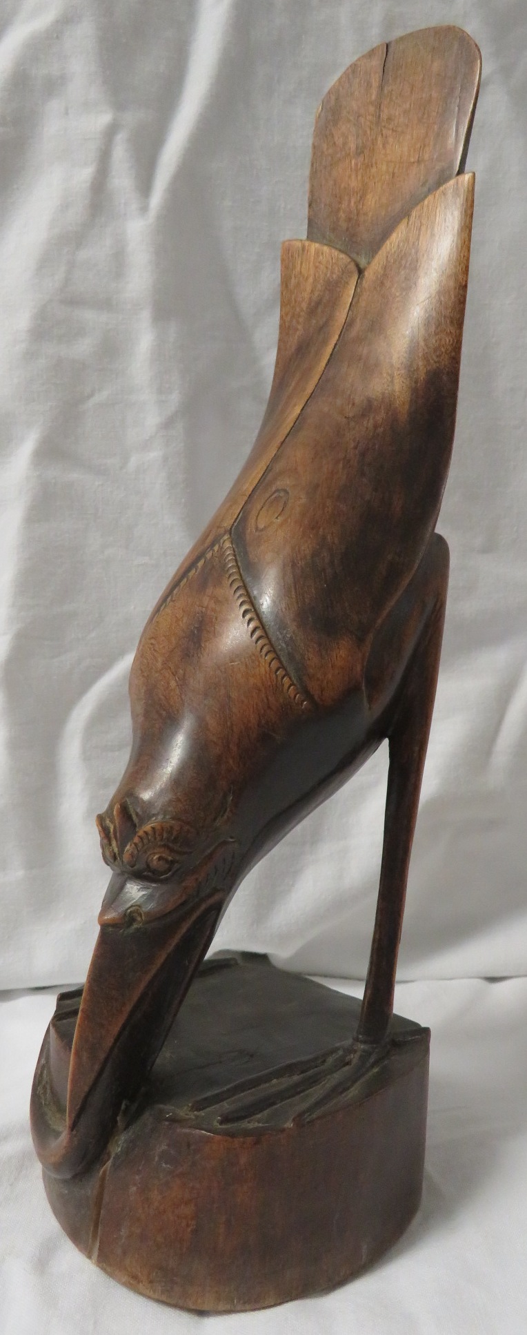 A finely carved figure of a bird with elongated tail eating lizard, perhaps Polynesian, height 28cm