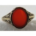 A yellow metal ring set with an oval carnelian (about 9mm x 8mm), pierced at the shoulders, the