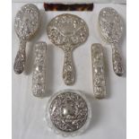 A dressing table set with repousse silver backs comprising hand mirror, four brushes, comb and
