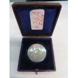 A WHITE METAL DISK WITH 1953-54 ENGRAVING INSET WITH A GEORGIAN COIN, IN PRESENTATION CASE; TOGETHE