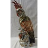 Large porcelain model of a cockatoo seated on a branch and outcrop with fruit, polychrome glaze, the