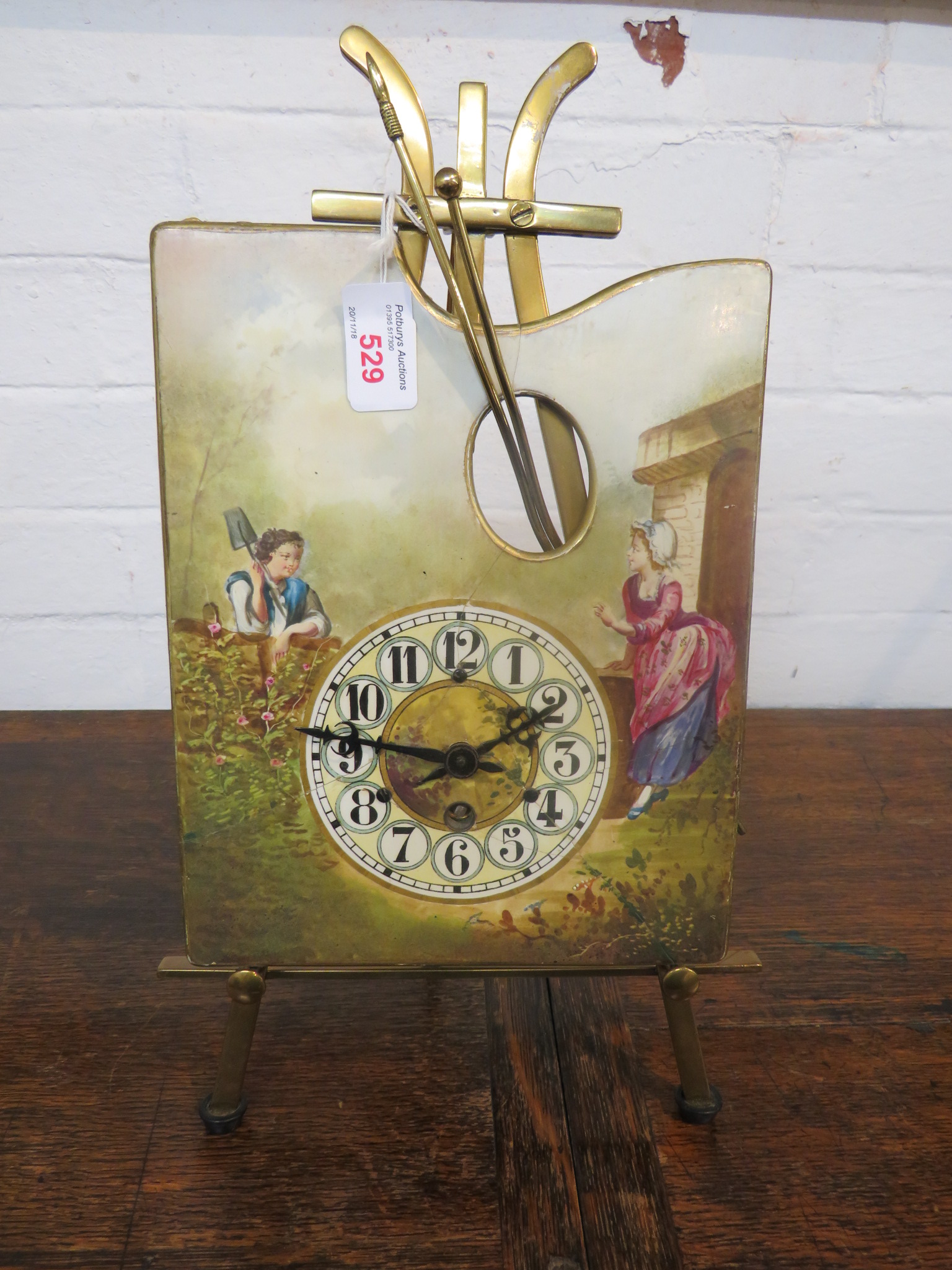 Brass and enamelled porcelain table clock as an artist's palette on easel, the dial painted with a