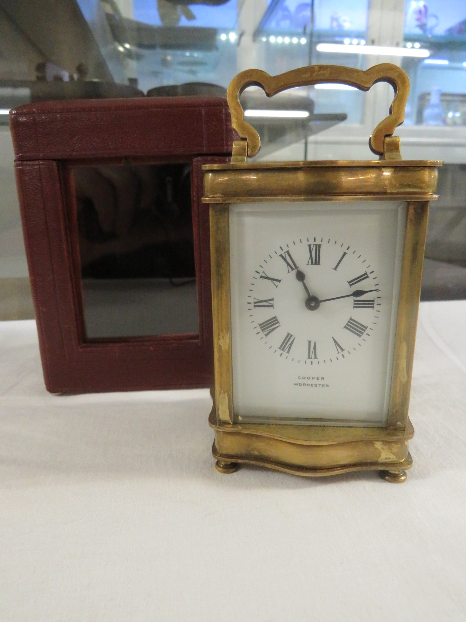 A brass serpentine cased carriage clock raised on bun feet, the dial signed Cooper Worcester, the