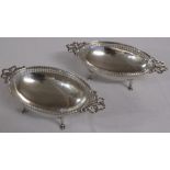 A pair of silver oval bonbonier with pierced rims, bow handles, and raised on hoof feet, marks for