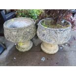 PAIR OF COMPOSITE STONE POTS ON PLINTHS, ONE WITH CONTENTS