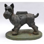A vintage cast iron shoe scraper in the form of a Scottish Terrier dog cocking its leg on oval base,