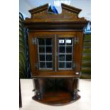 A reproduction oak corner unit with broken arch top and leaded glazed doors above a columned mirror