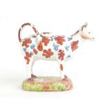 19th Century Yorkshire pottery cow creamer decorated in red and blue (loss to end of both horns,