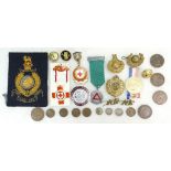 A collection of metal military cap badges, Gibraltar patch, enamelled Red Cross medals,