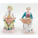 Pair of Wedgwood figural Salt Cellars, decorated and modelled as a seated man and woman,