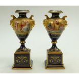 Pair of Vienna porcelain small two handled urns on stands, handpianted biblical scenes by L Jackl,