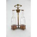 Art nouveau copper and brass TANTALUS - A two bottled tantalus, with cut / faceted decanter bottles,