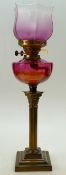 Early 20th century Corinthian column brass oil lamp with cranberry glass reservoir and shade.