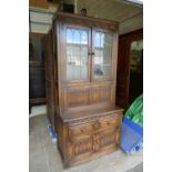 A 20th century oak linen fold display unit with leaded glazed stained glass two door top,