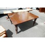 An early 20th century oak wind out dining table with two leaves on casters.