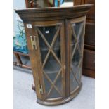 A bow fronted oak corner cupboard.