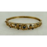 9ct hallmarked gold bangle with floral decoration, set sapphires. 14.1g.