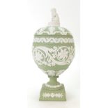 Wedgwood green Jasperware urn and cover decorated all around with scrolling foliage with cupid to