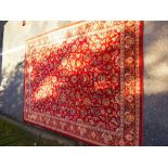 Red ground carpet having all over decoration 331cm x 25cm and a woollen green and cream rug