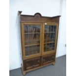 An old oak display cabinet having leaded glass doors with cupboard below