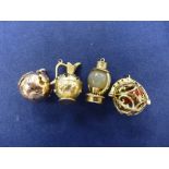 Four 9ct yellow gold charms including an agate and gold, miniature oil lamp, ewer inset garnets, etc