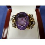 Unusual dress ring set with a large amethyst flanked by 6 diamonds on a yellow coloured metal shank,