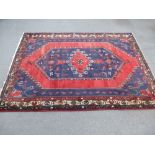 An Afghan red ground rug with geometric central motif decoration of birds and flowers