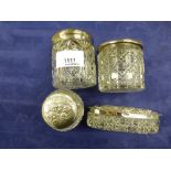 Four cut glass toilet jars with silver embossed lids including Edwardian examples with cherub