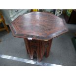 A Burmese red lacquer octagonal table on folding base having a flower decoration, 74cms