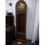 A vintage Gustav Becker oak long case clock having circular brass dial and rounded top with carved