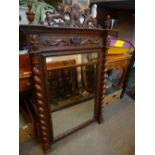 A Victorian carved oak wall mirror having barley twist column sides, 87cms