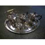 A silver plated four piece tea set and a plated kettle on stand