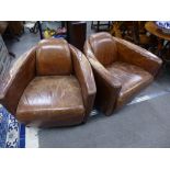 A pair of leather tub chairs on square legs.