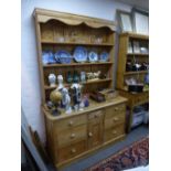 An old stripped pine dresser and rack back with seven drawers, 133 cms