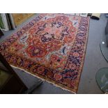 An antique Persian carpet with central medallion in a red field with stylised decoration, blue