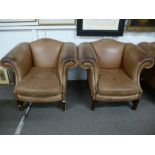 A pair of brown leather arm chairs on square moulded supports