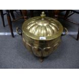 An old brass coal bin and lid on three paw feet