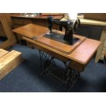 An oak cased singer sewing machine, the moulded table with two small knobbed drawers on pierced cast