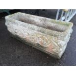 A rectangular composition stone garden plant trough, cast with classical decoration, with gryphon